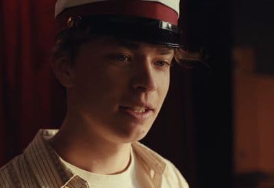 a young man wearing a sailor's hat in a dimly lit room