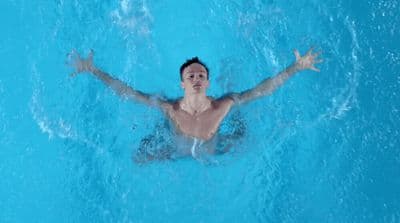 a man swimming in a pool with his arms outstretched