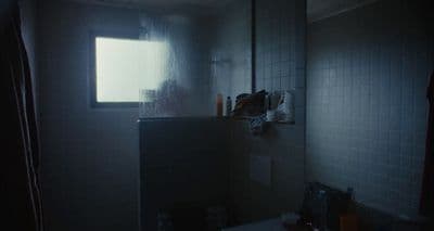 a dark bathroom with a window and a sink