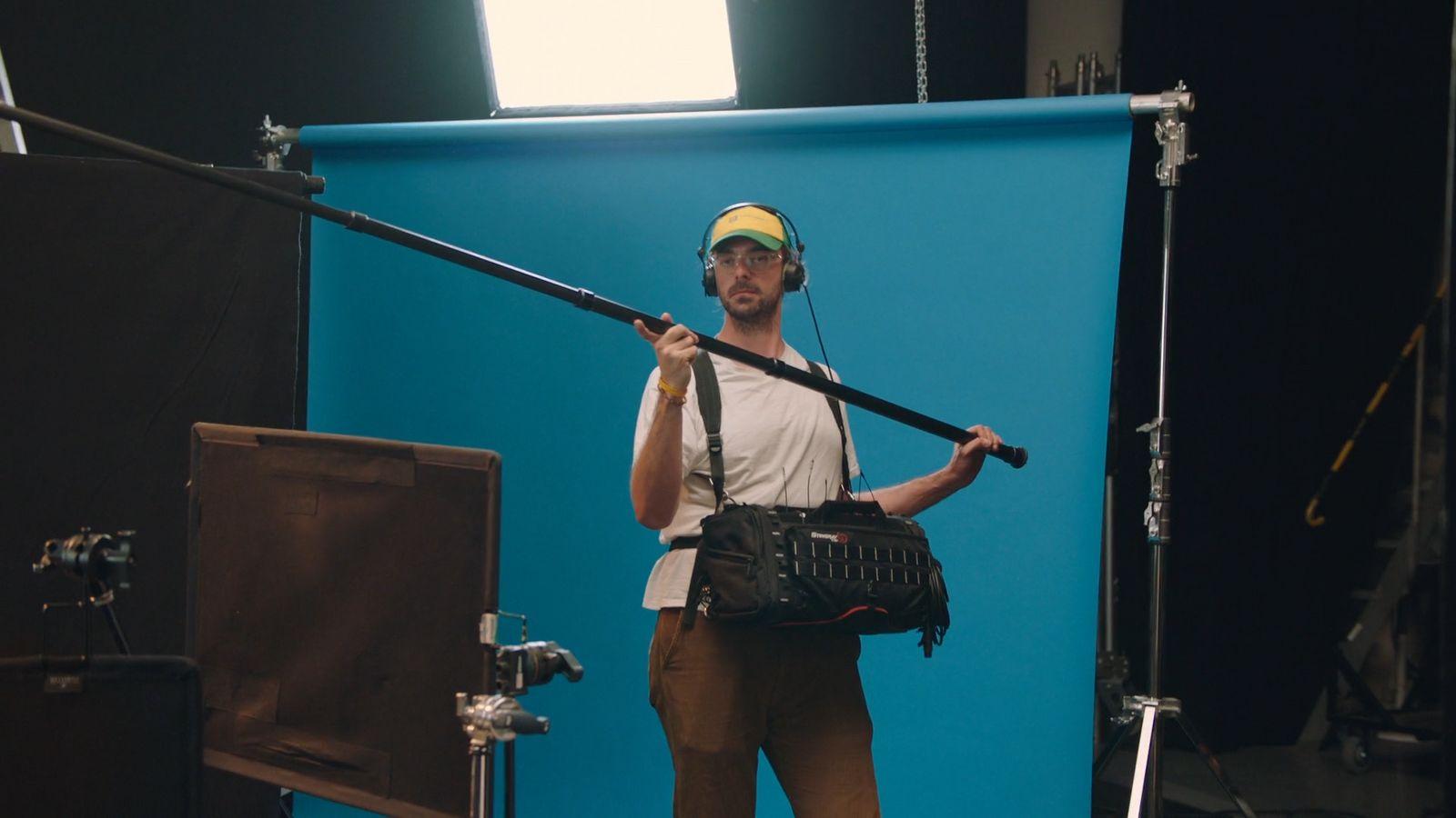 a man is holding a camera in front of a blue backdrop