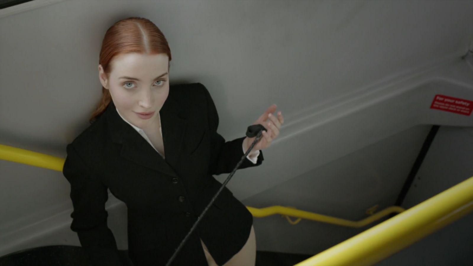 a woman in a black suit is standing on a yellow rail