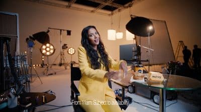 a woman sitting at a table in front of a camera