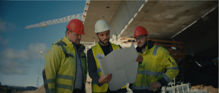 three men in hardhats are looking at a blueprint
