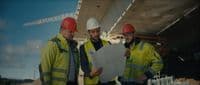 three men in hardhats are looking at a blueprint