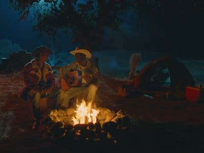 a couple of people sitting around a fire