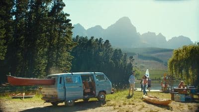 a van parked on a dirt road next to a forest