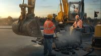 a couple of men standing next to a bulldozer