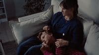 a woman sitting next to a child on a couch