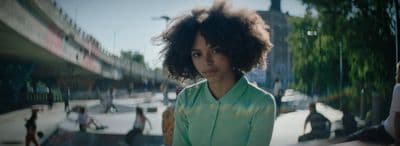 a woman with curly hair standing in front of a building