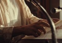 a person sitting at a desk with a book in front of a microphone