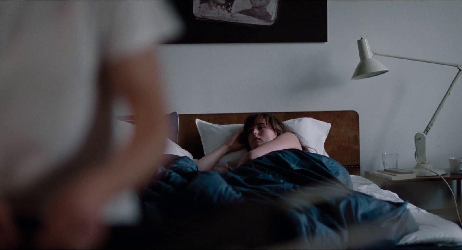 a woman laying in bed with her head on the pillow