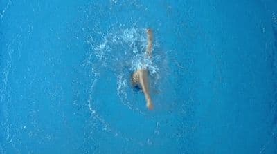 a person is swimming in a pool with blue water