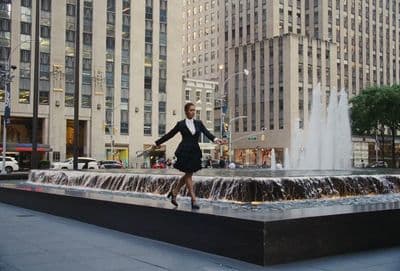 a woman in a black dress standing in front of a fountain