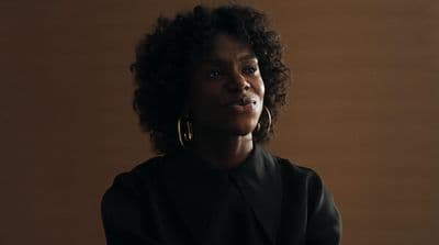 a woman in a black jacket and gold hoop earrings