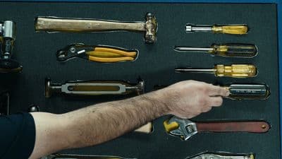 a man holding a wrench in front of a display of tools