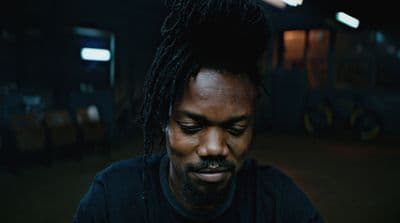 a man with dreadlocks looking down at his cell phone
