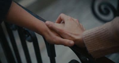 two people holding hands on a railing