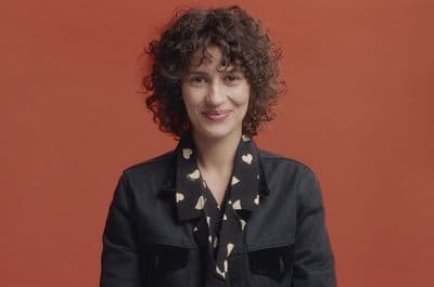 a woman with curly hair wearing a black jacket