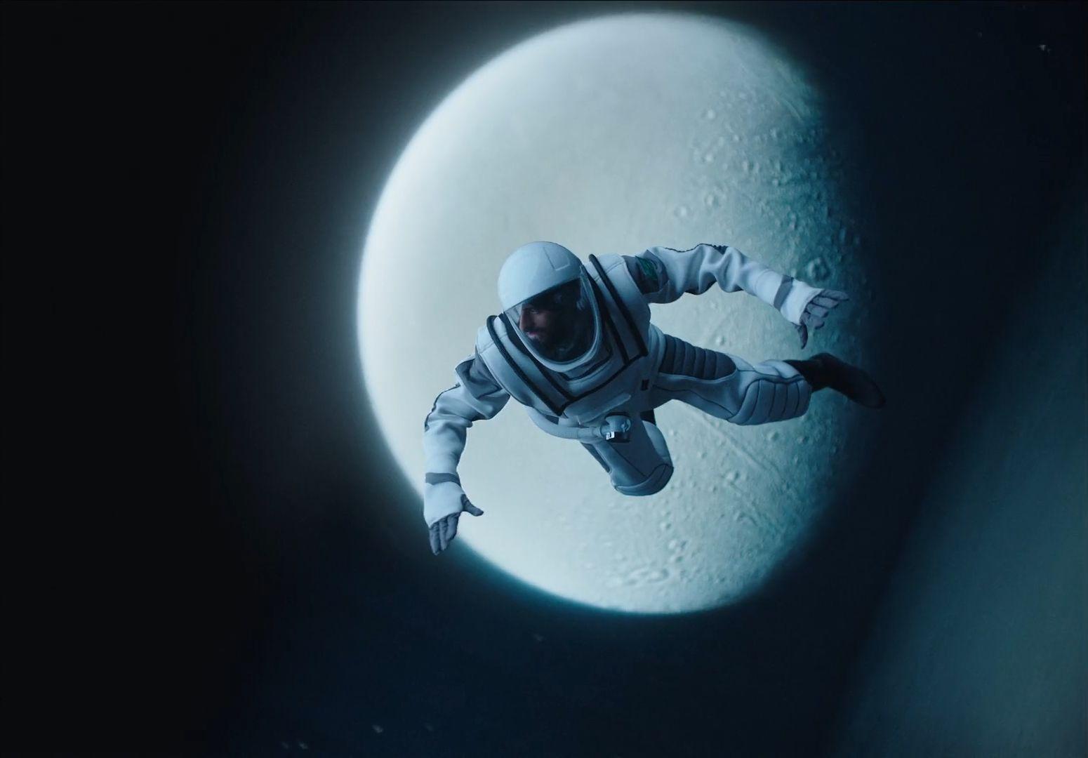 a man in a space suit floating in front of a moon