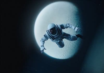 a man in a space suit floating in front of a moon