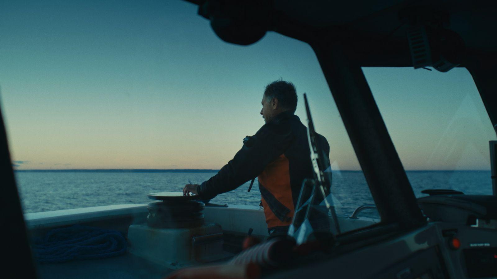 a man standing on a boat looking out at the ocean