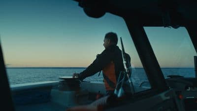 a man standing on a boat looking out at the ocean