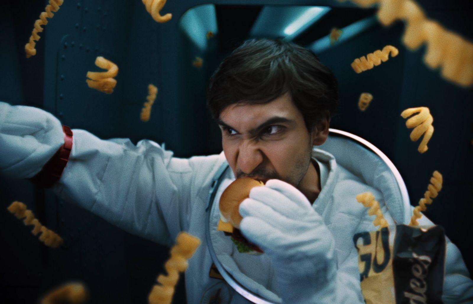a man in a space suit eating a hot dog
