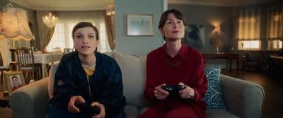 two women sitting on a couch playing a video game