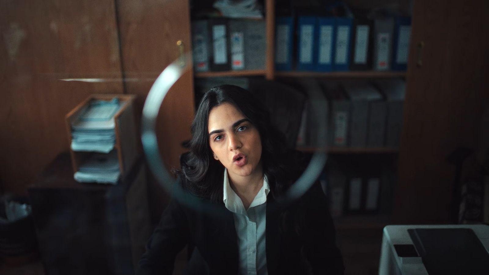 a woman sitting at a desk looking through a magnifying glass