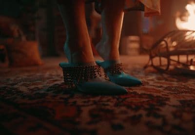 a woman's feet in blue high heels standing on a carpet