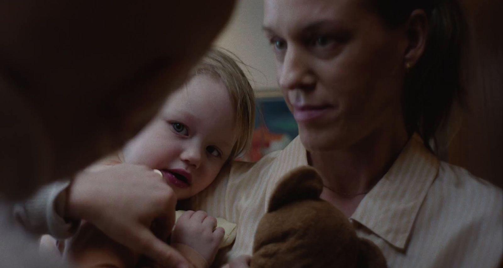 a woman holding a little girl who is holding a teddy bear