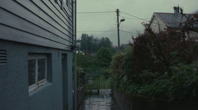 a rain soaked street next to a house