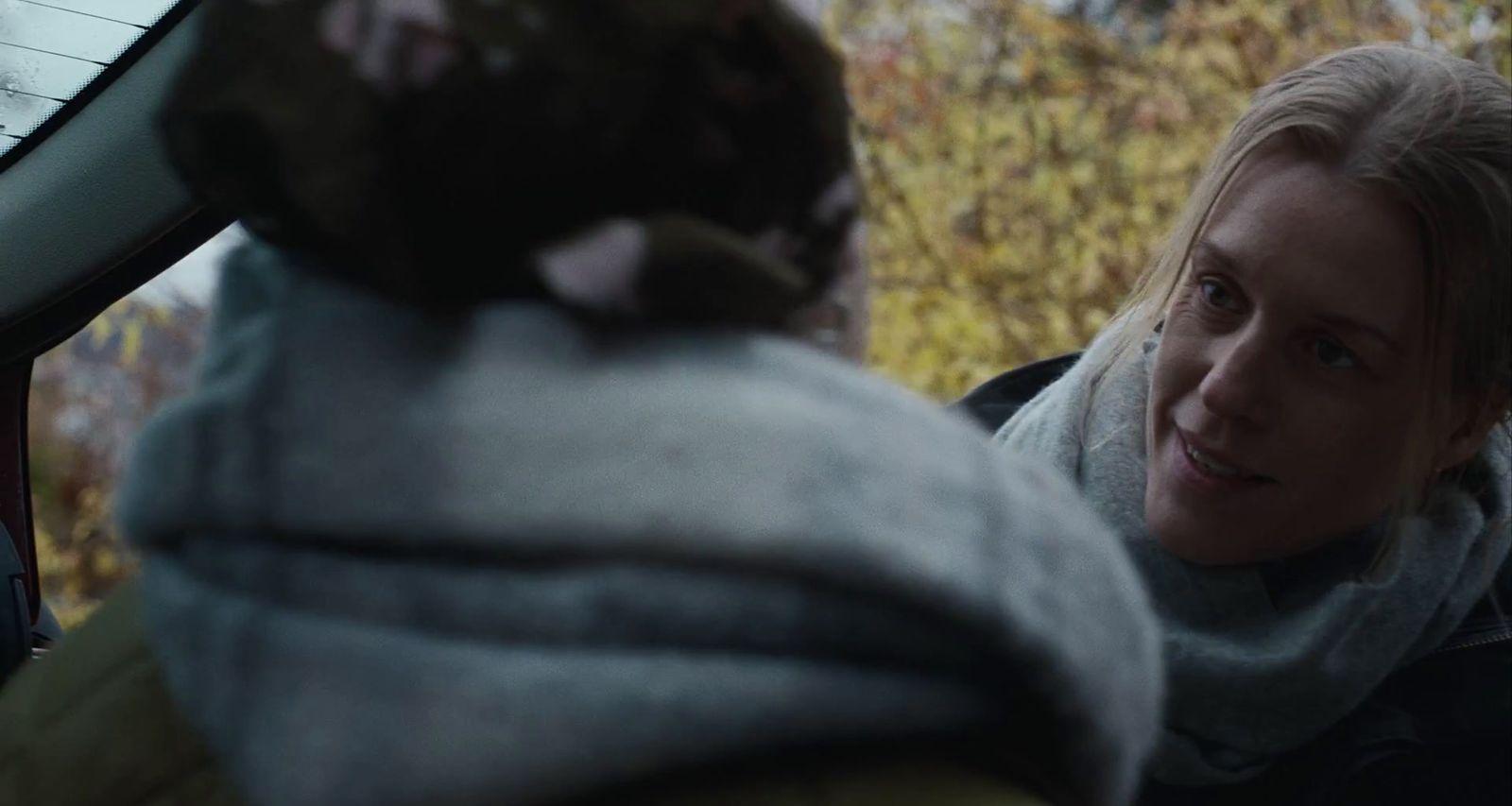 a woman sitting in the back of a car talking to a man