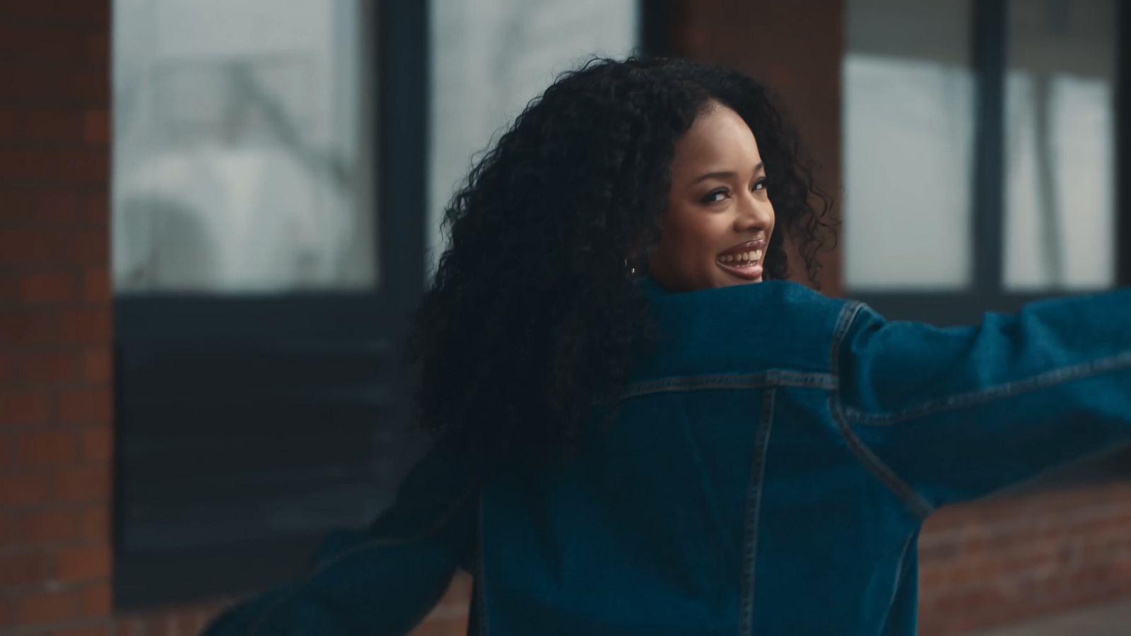 a woman in a blue jacket is holding her arms out