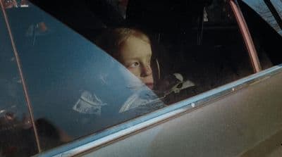 a little girl sitting in a car looking out the window