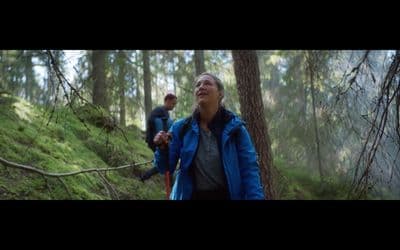 a woman in a blue jacket walking through a forest