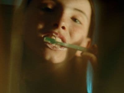 a woman brushing her teeth with a toothbrush