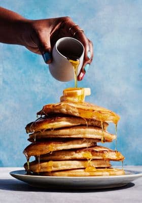 a stack of pancakes with syrup being poured on top