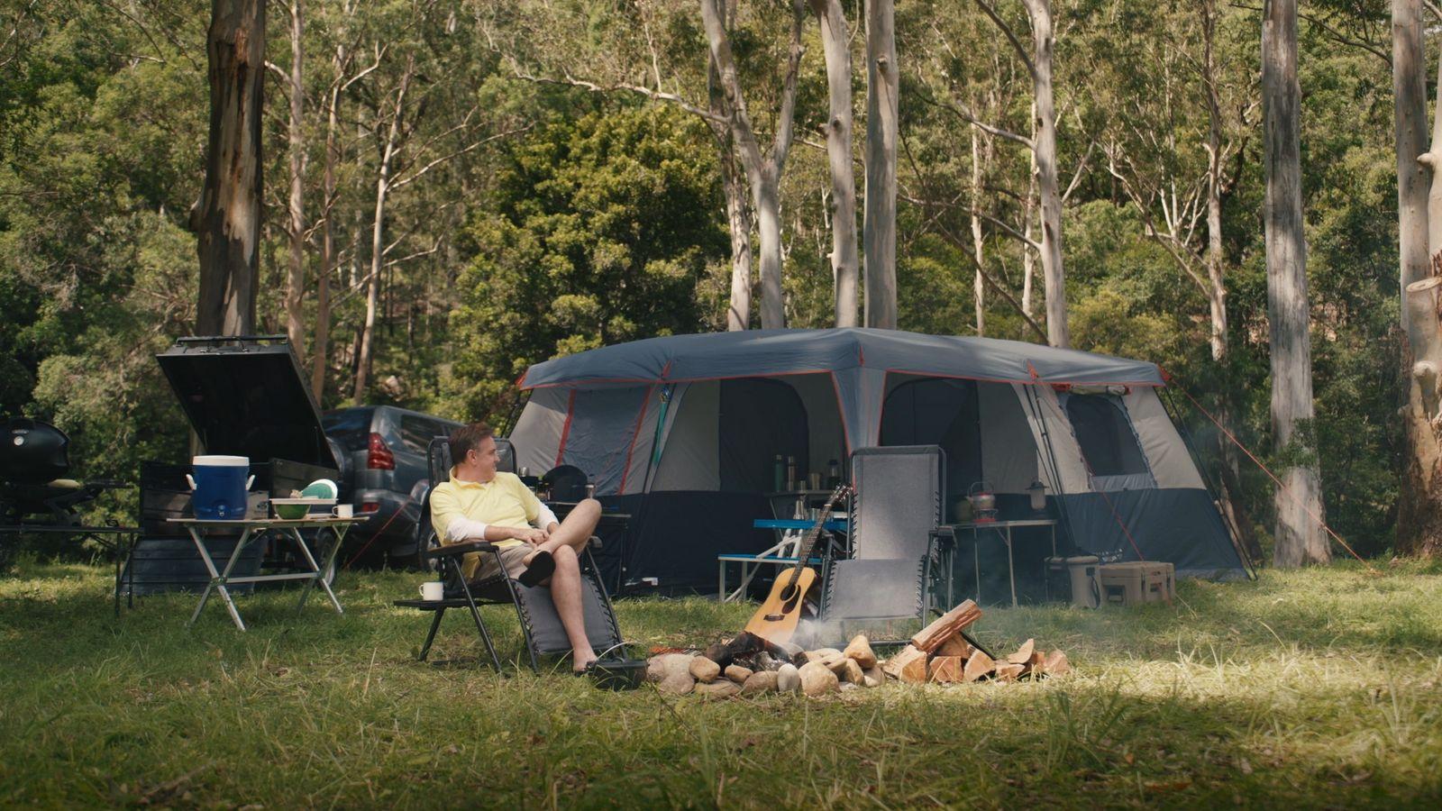 a man sitting in a chair in front of a tent
