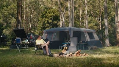 a man sitting in a chair in front of a tent