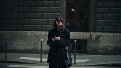 a woman standing on a street corner looking at her cell phone