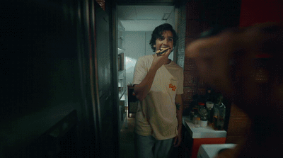 a man standing in a kitchen brushing his teeth