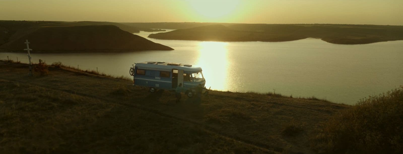 a van parked on the side of a hill near a lake