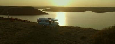 a van parked on the side of a hill near a lake
