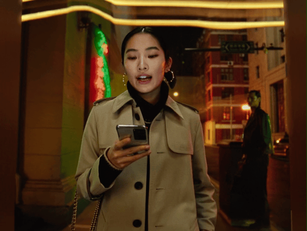 a woman in a trench coat looking at her cell phone