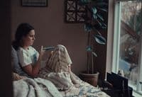 a woman sitting on a bed in front of a window