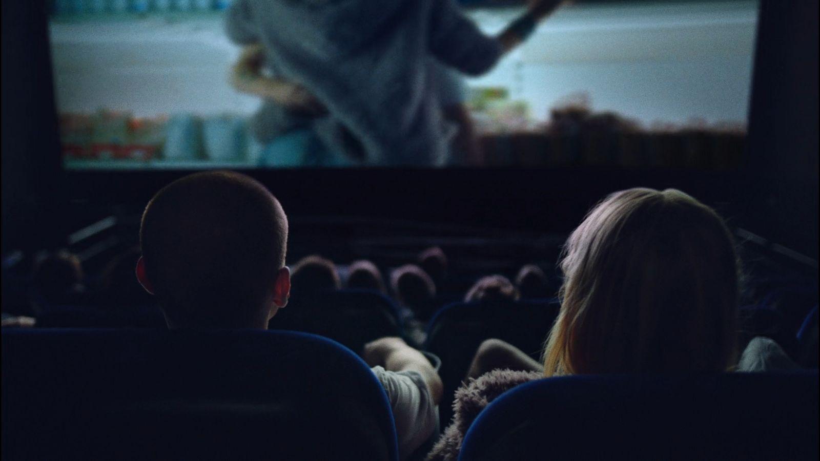 two people watching a movie on a large screen