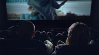 two people watching a movie on a large screen