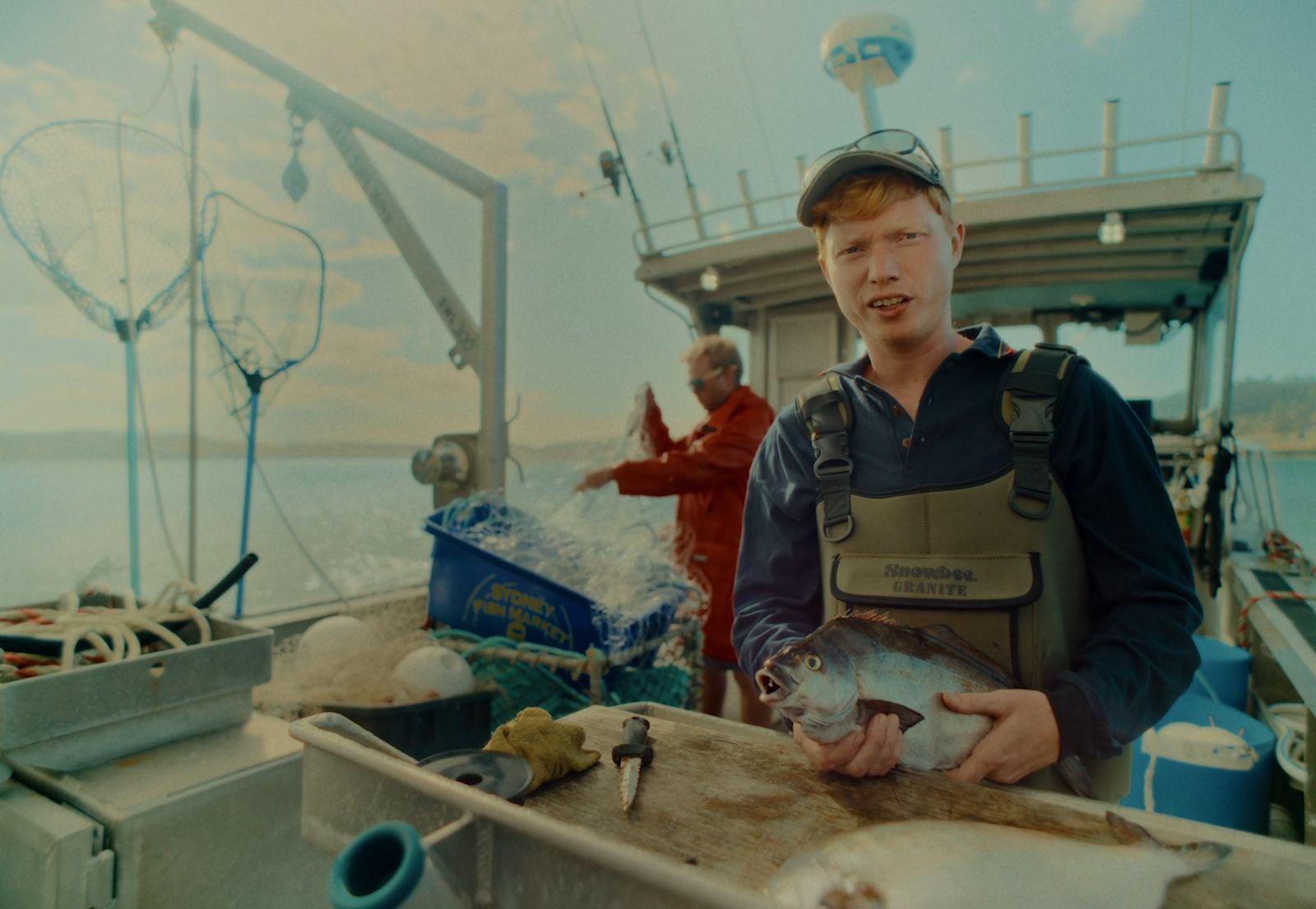 a man standing on a boat holding a fish