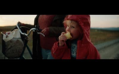 a little girl eating a piece of food next to a bike